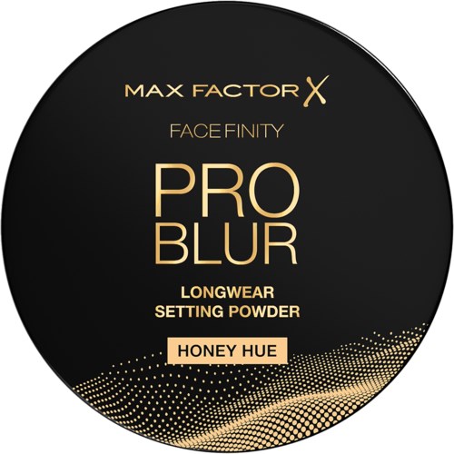 En rund svart förpackningsetikett för Max Factor ansiktsinställningspuder, honungston, med guldtext och prickad vågdesign.