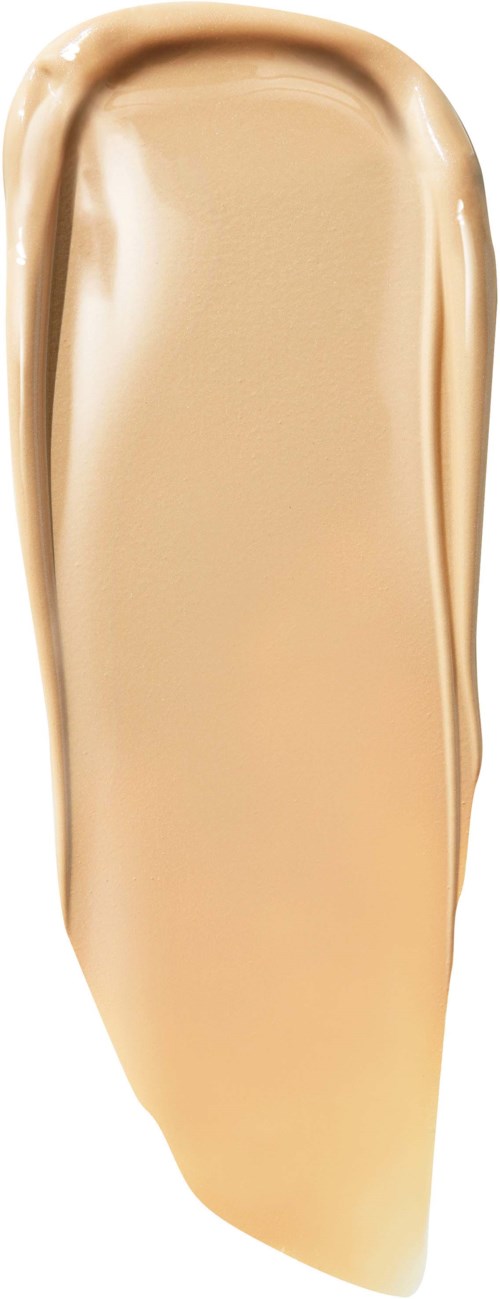En teststräng med beige krämig vätska, troligen foundation eller concealer, med slät textur på vit bakgrund.