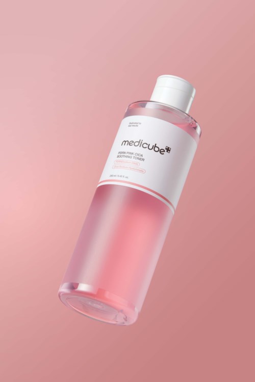 Eine rosa-weiße Flasche mit medicube-Toner vor rosa Hintergrund.