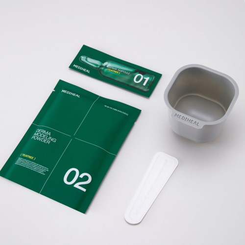 A skincare kit with green packaging, a small container, spatula, and a packet labeled 01 and 02.