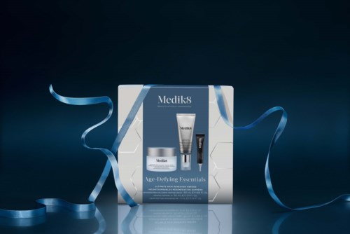 Medik8 hudpleiesett med tre produkter, pyntet med blå bånd på en reflekterende overflate.