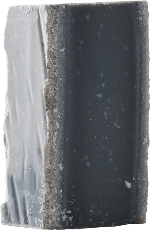 En vejrbidt metaloverflade med en mørk sektion og nogle lyse pletter, viser rust, snavs og korrosion.
