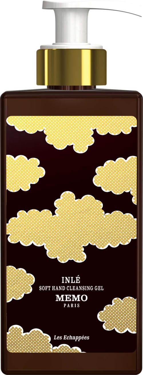 A brown bottle with a gold cap and a pump, decorated with yellow cloud patterns, labeled 'MEMO PARIS' and 'Les Echappées.'