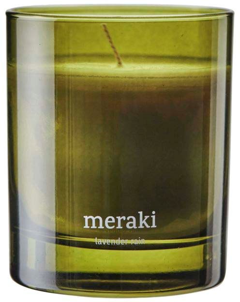 Et grønt glasstager med et tent lys indeni. Der står "meraki" og nævner lavendelduft.