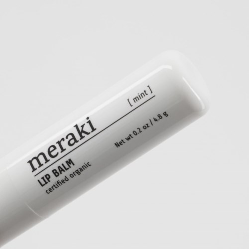 En hvit tube merket 'meraki' med 'LIP BALM' og 'mint' duft, inneholder 0,2 oz økologisk balm.