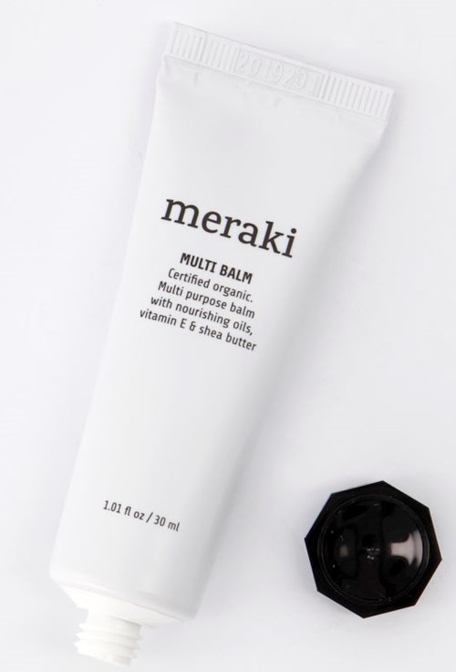 En hvit tube merket 'meraki' med svart lokk ved siden av, inneholder flerbruks nærende balm for huden.