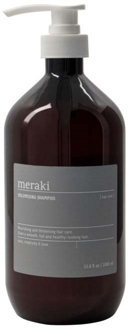 En mörkbrun schampoflaska med vit pump och grå etikett, märkt "meraki" för vård av näringsrikt hår.