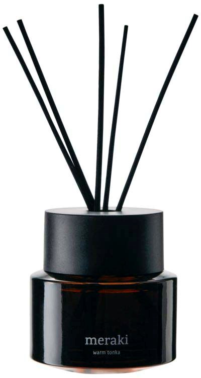 A black container with the word "meraki" and "warm tonka" on it, with black sticks or reeds coming out.