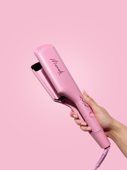 Een hand houdt een roze stijltang vast tegen een roze achtergrond.