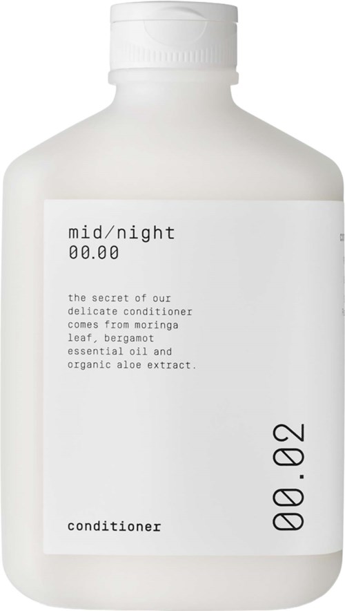 En vit flaska med balsam med minimalistisk etikett som nämner ingredienser som aloe, bergamot och eteriska oljor.