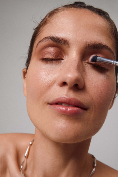 En kvinna har ögonen stängda medan en makeuppensel används på hennes ögonlock.