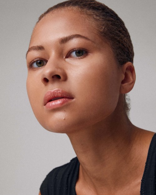 A woman with clear skin and smooth hair is looking calmly at the camera.
