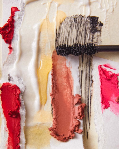 Textures of different colored paints and a paintbrush on a palette, showing various shades and brush strokes.