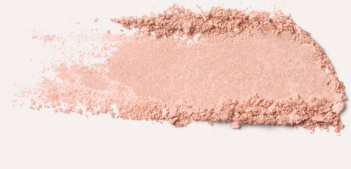 En puderliknande beige substans spridd på en vit yta, med ojämna kanter och några lösa partiklar runt omkring.