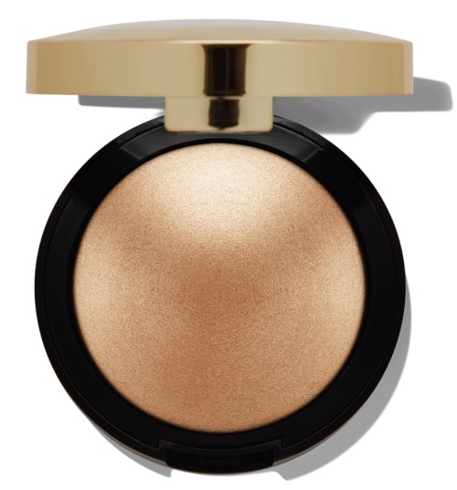 A round, beige face highlighter with a gold lid, in a black compact. It has a smooth, shimmery surface.
