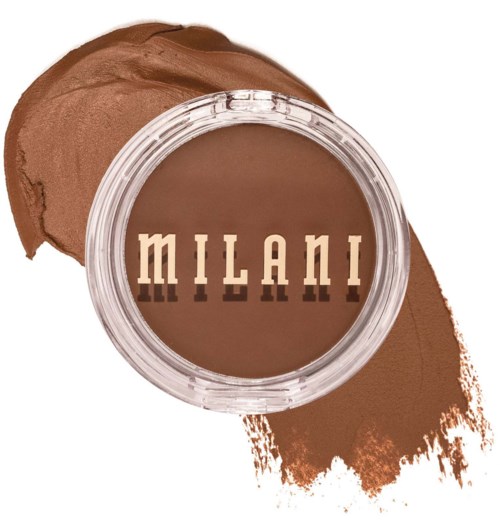 Ein kleiner runder Behälter mit dem Wort 'Milani' darauf, umgeben von brauner Kosmetik oder Creme.