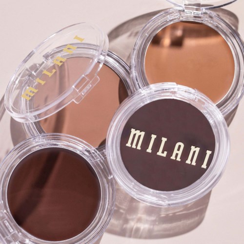 Tre beholdere med sminke er plassert på en overflate, med en merket "MILANI" og en annen "ALTERNA."