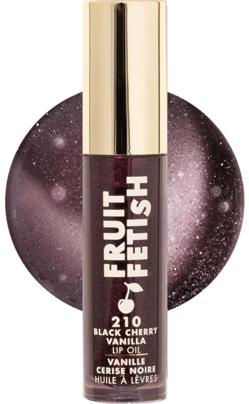 Huulirasva putkilossa, jossa kultainen korkki, merkintä "Fruit Fetish Black Cherry Vanilla." Tumman violetti pakkaus tähtitaivaan taustalla.