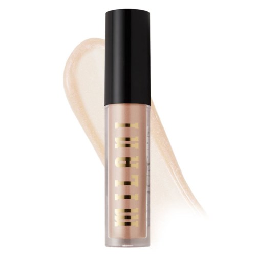 En tub med beige flytande concealer med svart lock och guldig text, placerad på ljus bakgrund med en beige streak.