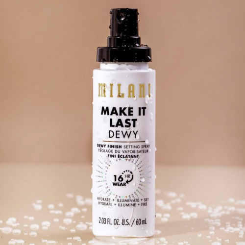 En vit sprayflaska med svart spraymunstycke och guld och svart text, står på en yta med spilld vätska.