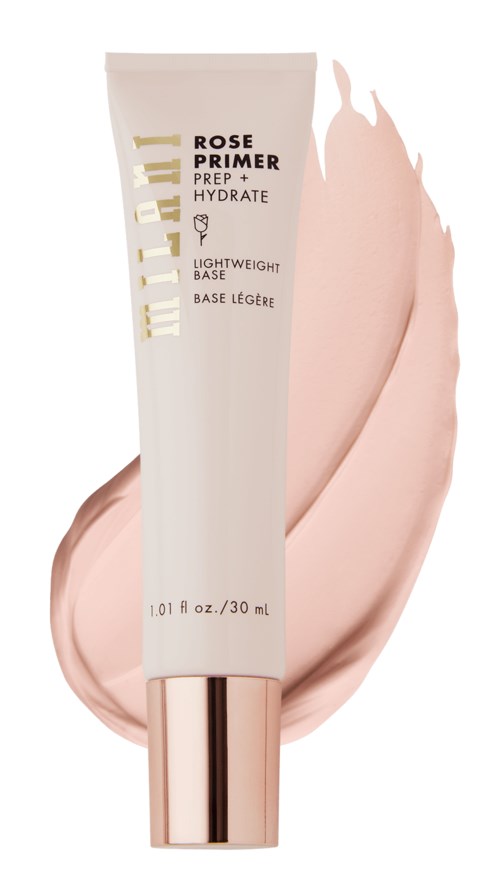 En tub med makeup primer bredvid ett drag av rosa grundfärg eller kräm. Tuben är vit med guld- och svart text.