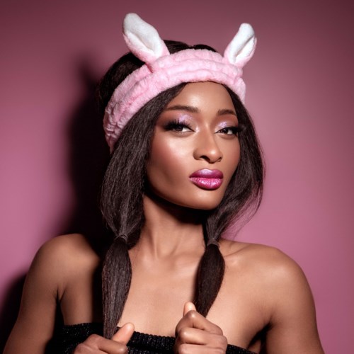 A woman with long hair, wearing a pink headband with bunny ears, gazes confidently at the camera.