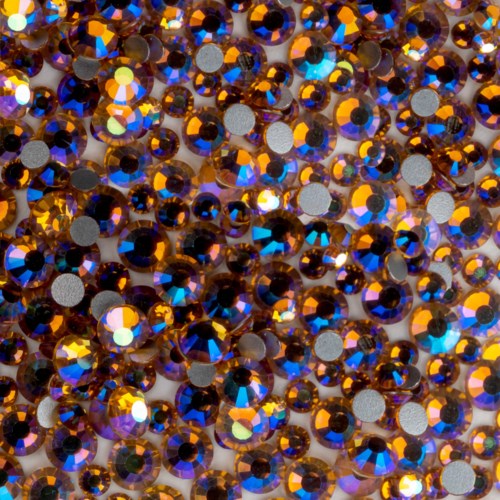 Mange små, glitrende, brune-oransje rhinestones med reflekterende, flerfargede overflater samlet.