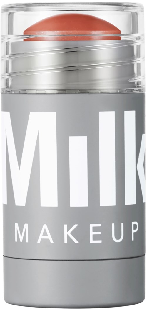 En lille, klar beholder med låg, mærket "Milk Makeup," indeholder en lyserød-brun æggeformet genstand.
