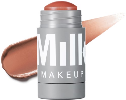 En grå beholder mærket 'Milk Makeup' med et ferskenfarvet produkt på toppen og en prøve bag den.
