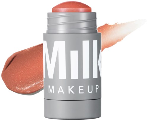 A silver tube labeled 'Milk Makeup' with a peach-colored balm or lipstick, and swatches of the product on white background.