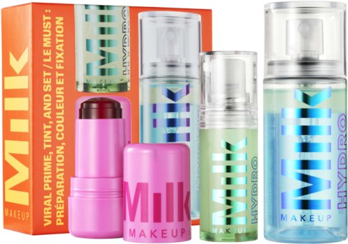 Set af fire små sprayflasker mærket som makeup-produkter, herunder Milk Hydro Grip og andre varer, med farverig emballage.