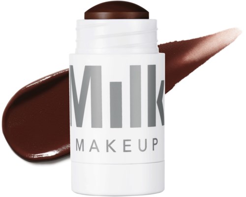 Valkoinen pakkauksessa lukee 'Milk Makeup' ja siinä on ruskea kansi, sekä ruskea huulipuna tai kerma tuote sen takana ja vieressä.