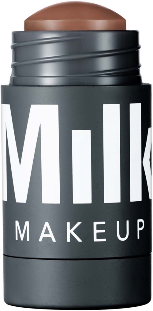 A stick of makeup labeled "Milk Makeup" with a brown top, partially twisted open. Black background.