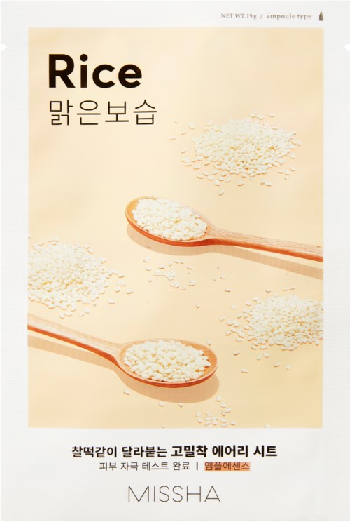 A packet of rice with scattered rice grains and two wooden spoons filled with rice.