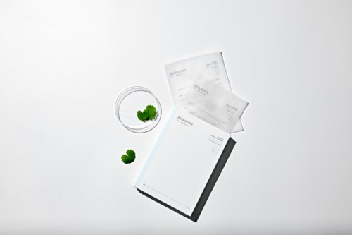 En medicinflaske med tabletter og to små grønne planter på hvid baggrund.