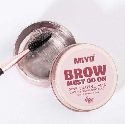 Valkoinen vahan säilytysrasia ja harja, merkattu "MIYO BROW MUST GO ON" kulmien muotoiluun.