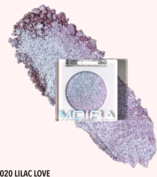 En skinnende lilla øjenskygge i kompakt med teksten "Moira" og "020 Lilac Love" under. Baggrund med lilla glitter.
