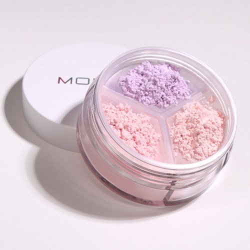 A round container with three sections holds purple and pink powdered cosmetic or skincare products.