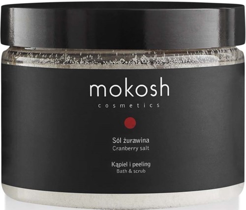 A jar labeled Mokosh cosmetics with cranberry salt, bath, and scrub ingredients, black lid, and simple dark label design.