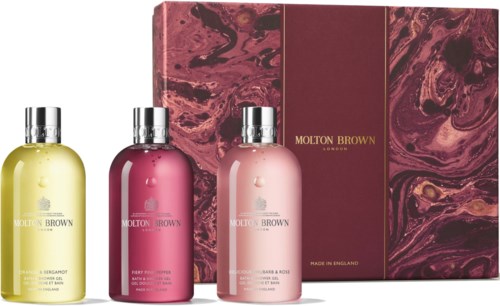 Three bottles of Molton Brown bath products in yellow, pink, and cream colors, with a matching box behind them.