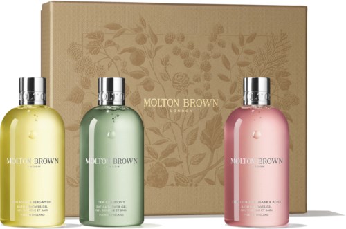 Three Molton Brown bottles in yellow, green, and pink stand in front of a beige box with floral design.