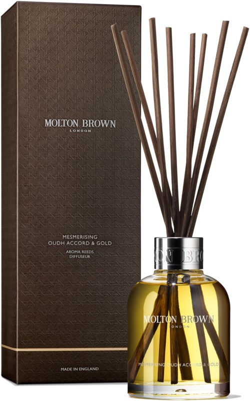 Eine braune Box und eine Glasflasche enthalten einen Raumduft mit Holzstäbchen. Labels zeigen Molton Brown.