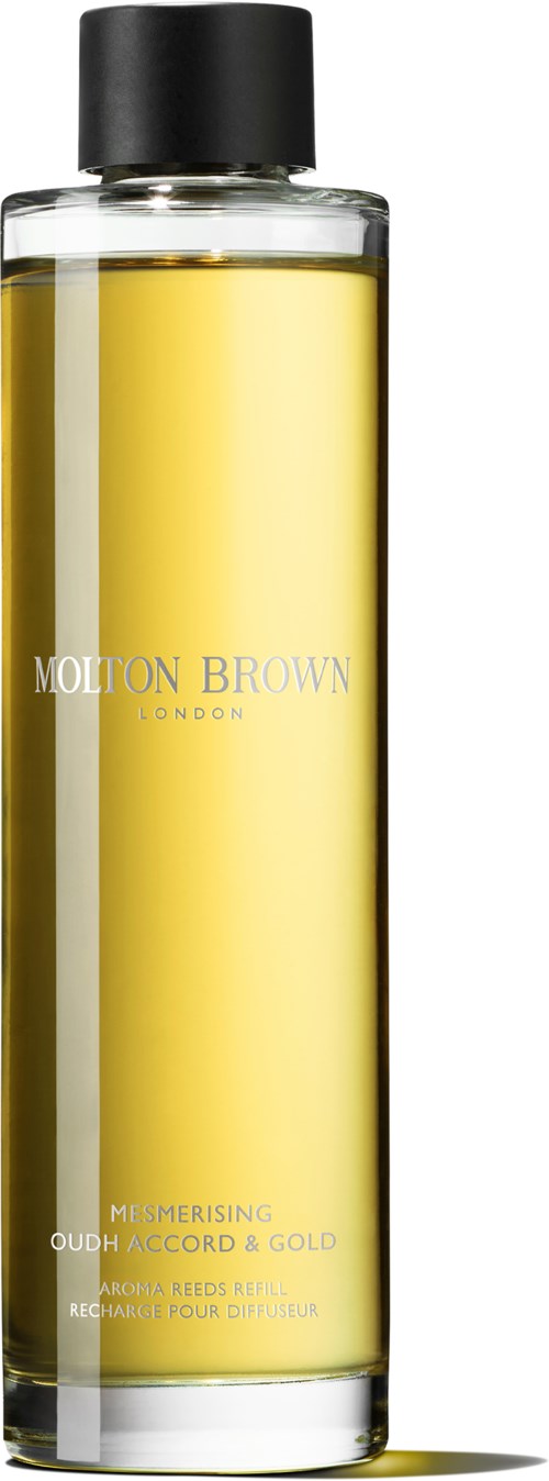 En lång glasflaska med svart lock och gul vätska inuti, märkt 'Molton Brown London'.