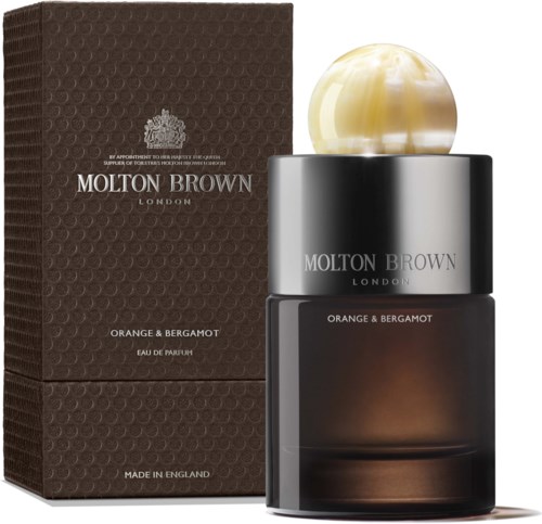 En parfume flaske med en stor gullagtig marmor hætte og en mørk beholder ved siden af en tekstureret boks.