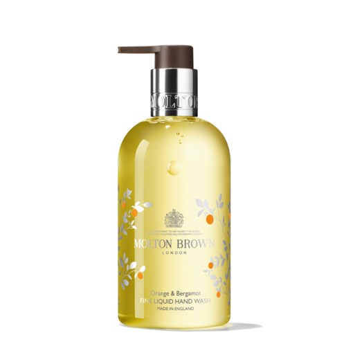 En gul vätskehandtvättflaska med en brun pump, dekorerad med orange och blå floral design, märkt Molton Brown.