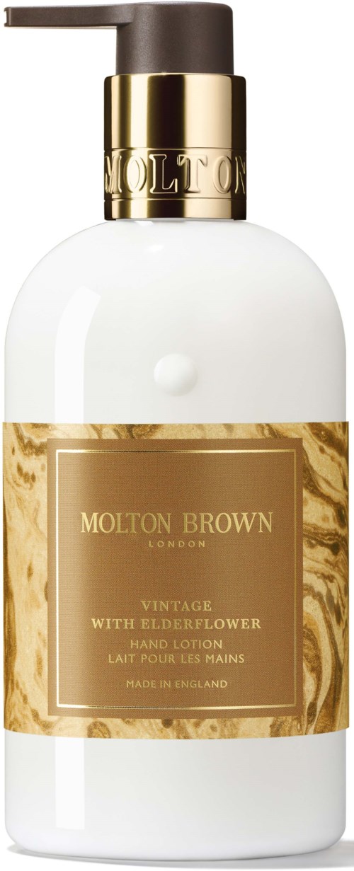 En hvid flaske med guld og mørkebrunt pumpe, mærket Molton Brown med hyldeblomsthåndlotion.