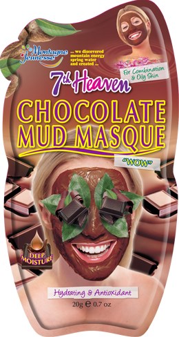En kvinne smiler med sjokolademudmaske i ansiktet, omgitt av sjokoladestykker og grønne blader.