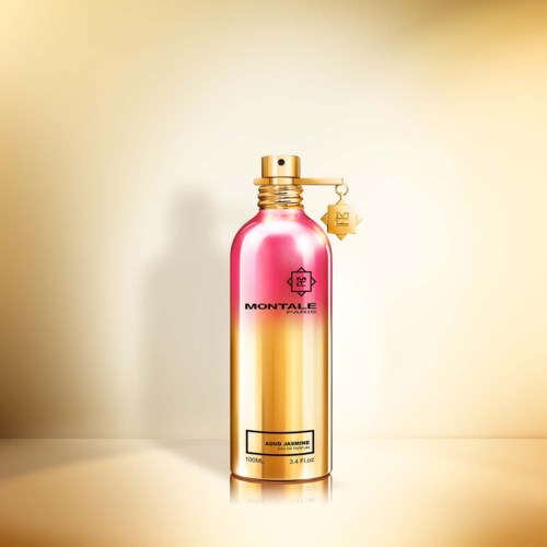 Ein glänzender rosa und goldener Sprühflasche mit Markennamen und Etikett, steht vor hellem Hintergrund.