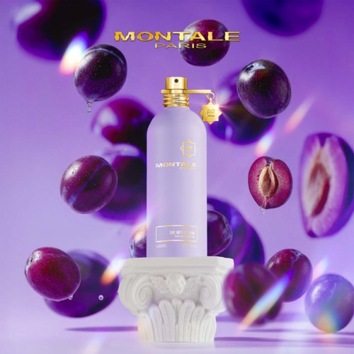 Ein Parfümflasche auf einem weißen Sockel mit lila Trauben drumherum und lila Hintergrund.