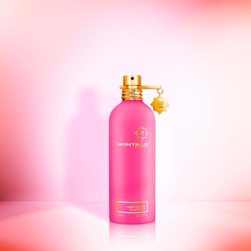 Eine pinke Flasche mit goldener Kappe und kleiners goldenen Charm, beschriftet 'Monteale' und 'Lucky Call' für Parfüm.